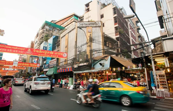 Driving bikes and cars on busy road with markets and asian stores