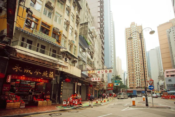 Local chinese shops and people walking on streets with tall concrete buildings in asian city