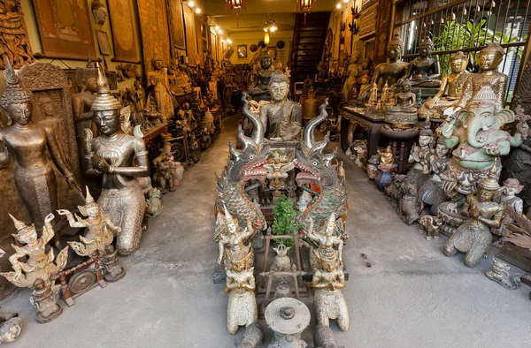 Vintage statues of Buddha and traditional wooden souvenirs in antique shop of thai city
