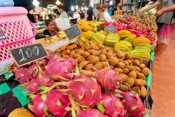People buying dragon fruits and tropical vegetables on street market with big choice of tasty food