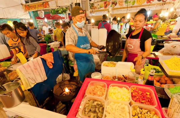 Street vendors and fast-food cookers sell exotic dishes with seafood and noodles on market