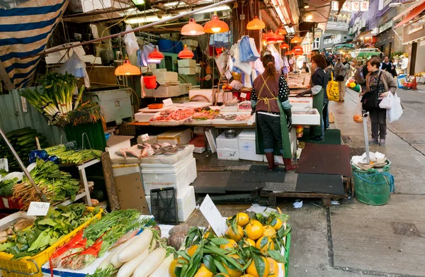 Customers of outdoor market choose seafood, fruits and vegetables on busy narrow street