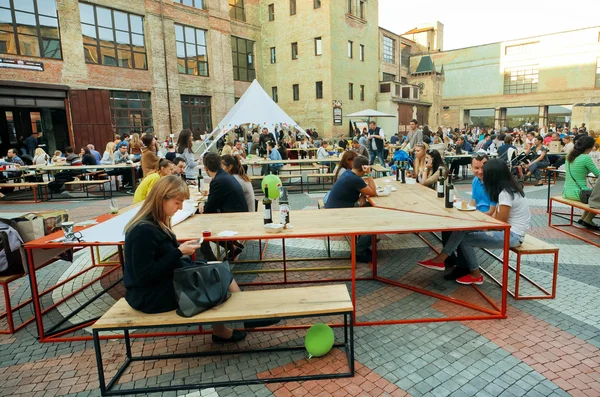 People having rest around tables of Street Food Festival at weekend