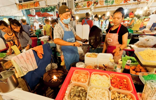 Street vendors and fast-food cookers sell exotic dishes with seafood and noodles on market