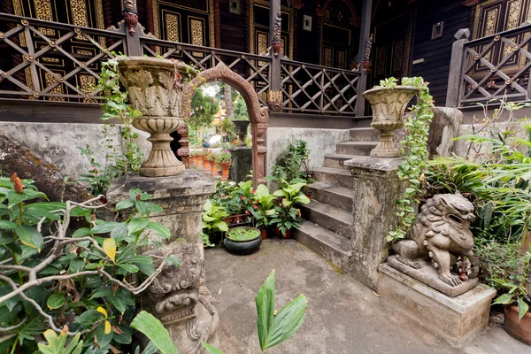 Old house courtyard in village of Thailand, with big mirror, stone steps and traditional statues