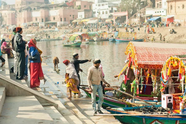 People crossing the river by riverboat of an old indian city