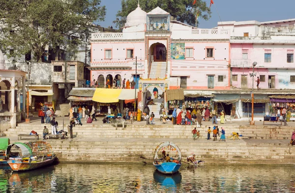 Old indian city buildings over the river with crowd of people outside