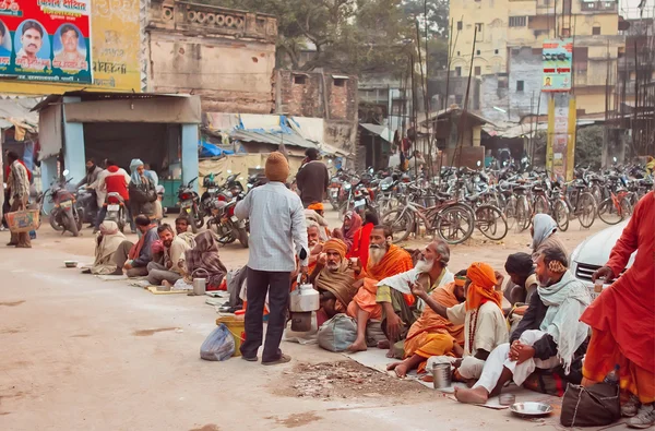 Poor people waiting for charity distributing food on the dirty streets of indian city