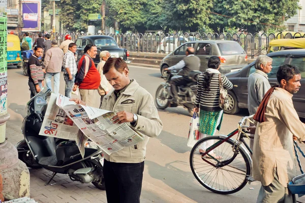 Man reading a newspaper in crowd of busy people on the street