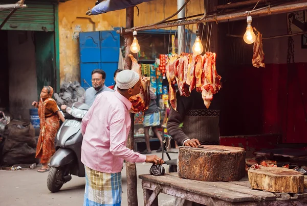 Elderly man watching on meat market stall of old indian city street