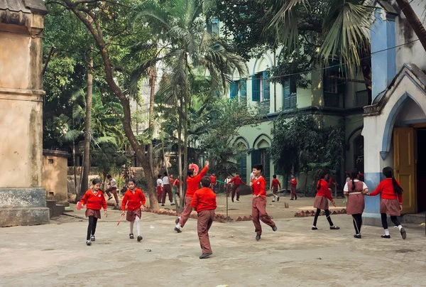 Schoolkids jumping with frisbee in green courtyard of school