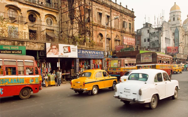 Traffic on indian road with markets and speeding antique Ambassador cars