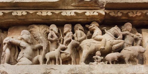 Village and rural people with animals on stone relief of Khajuraho temple, India. UNESCO Heritage site