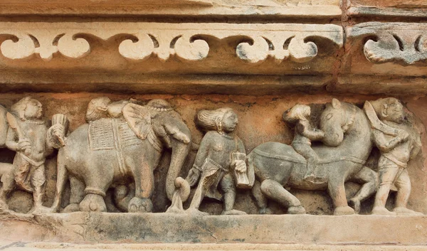 Procession of indian people, elephants on stone wall of Khajuraho temple, India. UNESCO Heritage site,