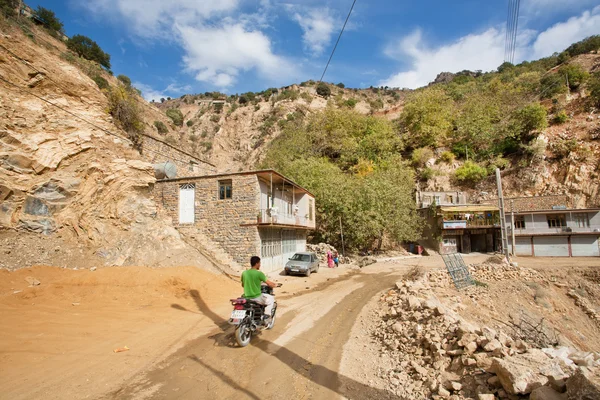 Racer on motorcycle rides through the mountain village