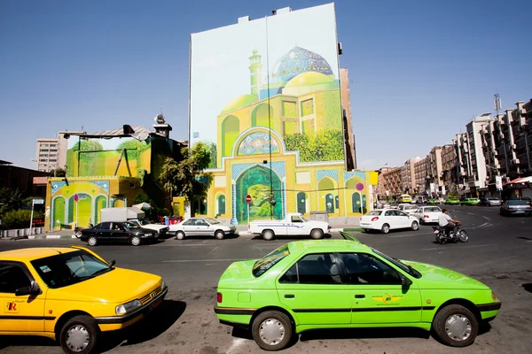 Traffic on sunny road with colorful taxi cars and street art on the building wall