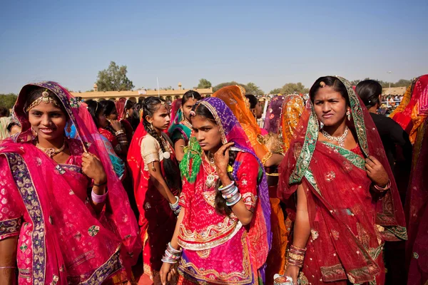 Beautiful women in red sari dresses going the Desert Festival