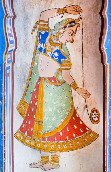 Woman in indian sari plays with toy yo-yo in fresco of ancient mansion