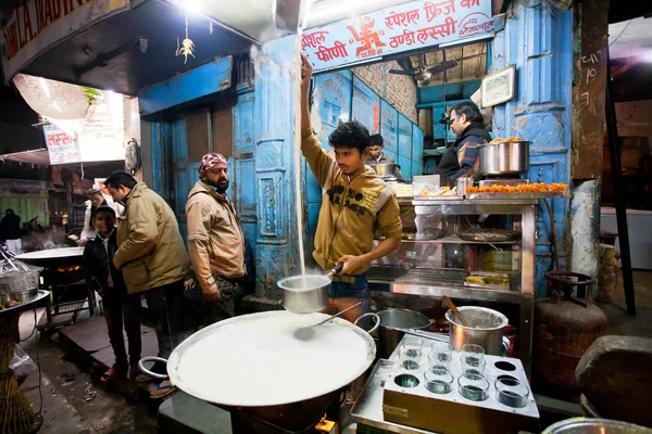 Young chef cooks milk with saffron near the street restaurant