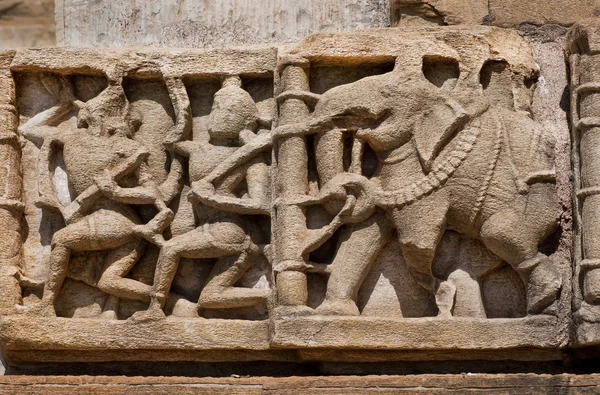 Carved in stone Indian elephant and the people on the ruined bas-relief on the wall of the temple