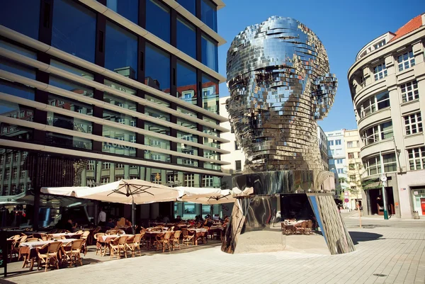 Outdoor cafe near  famous artist David Cernys sculpture Metalmorphosis in giant head form
