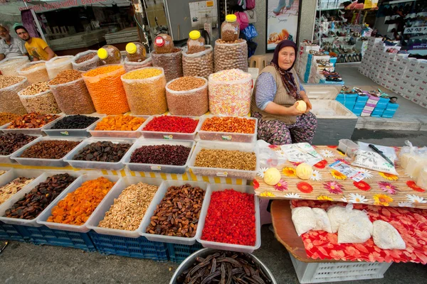 Elderly woman sells dried fruit and cottage cheese on rustic street market