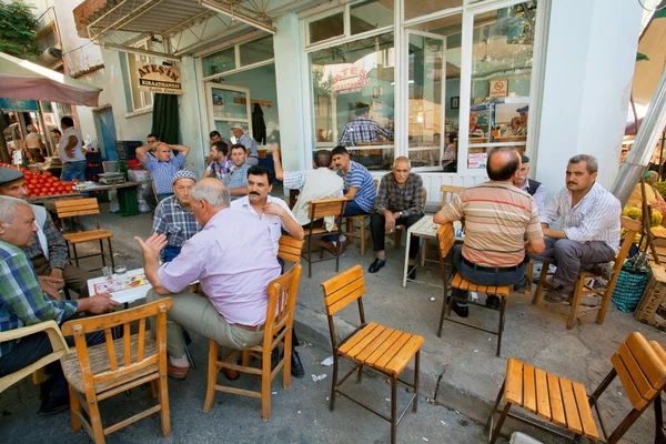 Senior men sitting around tables and talking in rustic cafe of village