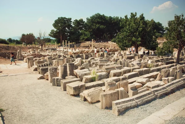 Carved columns and walls falled down from Greek-Roman empire time and tourists around Ephesus