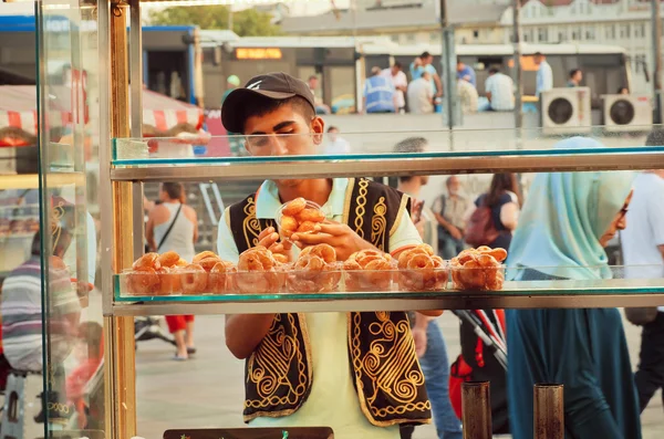 Sweets on street food stall with vendor in the traditional Turkish clothes