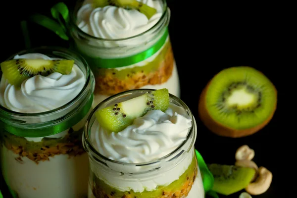 Natural sweet dessert with kiwi and nuts in glass jars on kitchen