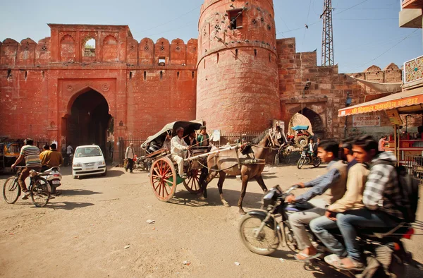 Traffic jam on dirt road of indian city with ancient brick gates