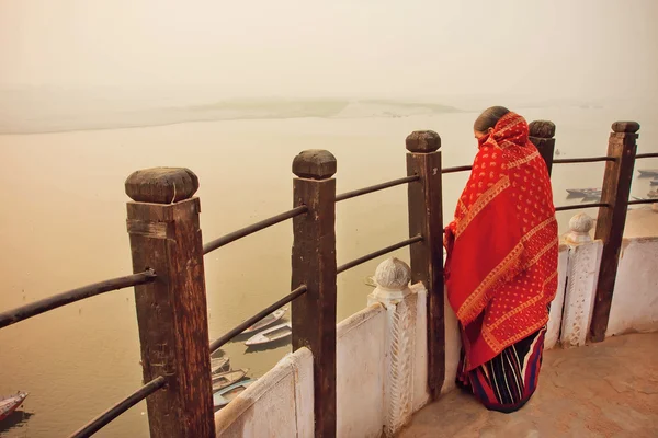 Lonely woman watching the natural landscape behind sacred waters of River Ganges in indian city Varanasi, India