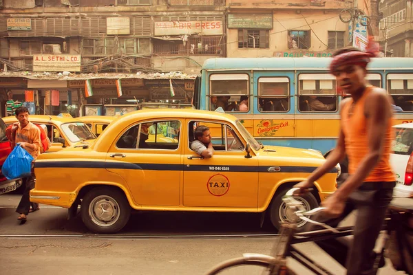 Yellow taxi car, buses and cyclists driving on the busy street of indian city