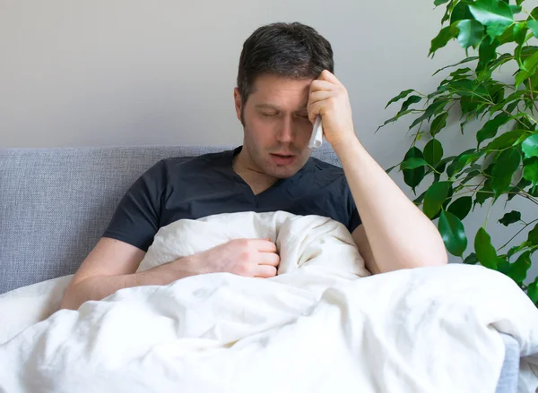 Sick man lying in the bed with fever.