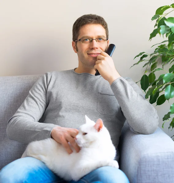Man relaxing on the sofa with tv remote control. Watching TV with his cat.