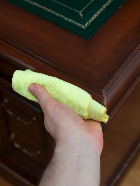 Man\'s hand wipes dust from antique furniture.