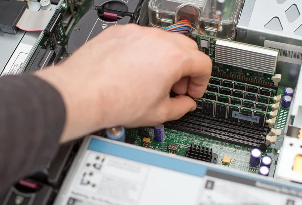 Computer technician installing RAM memory into motherboard.