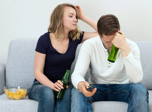 Sad couple watching sports match on tv.