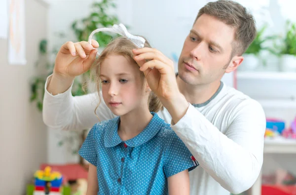 Father styling hair of his daughter at home.