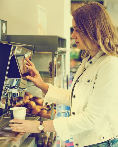 Pretty woman using coffee vending machine. Vintage effect.