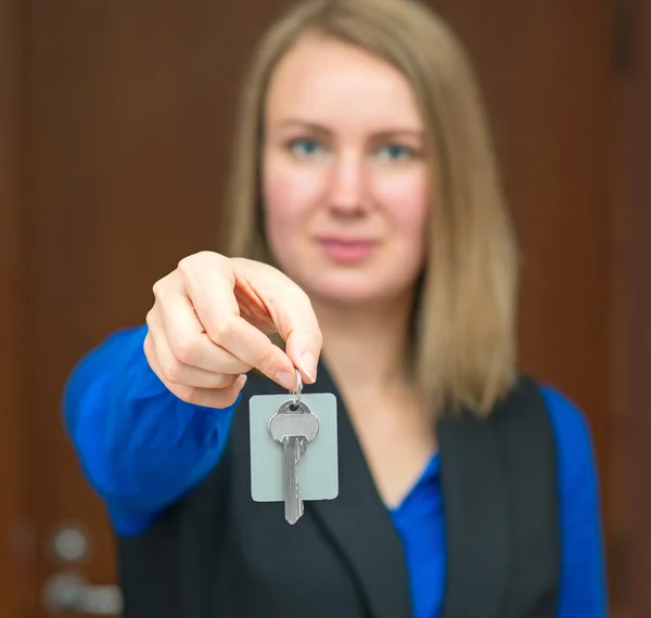 Hotel receptionist offering key from room.