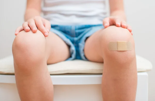 Child knee with an adhesive bandage.