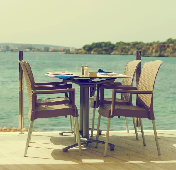 Empty outdoor street cafe by the sea. Vintage effect.