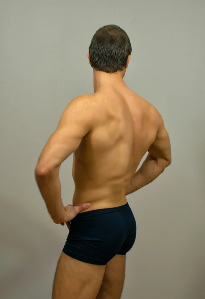 Muscular male model posing. Back view.