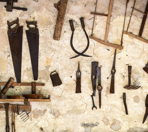 Wall with pile of vintage hand tools.