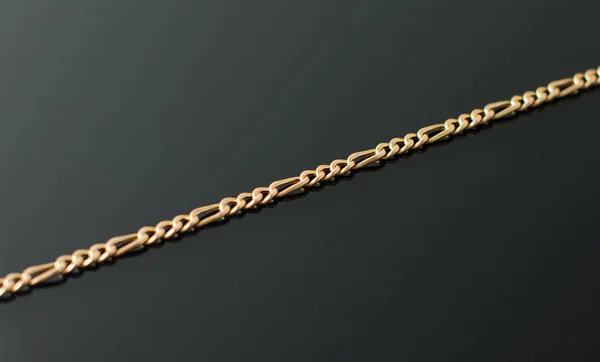 Gold chain lying on black table.