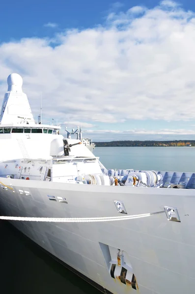 Moored white naval ship with gun.