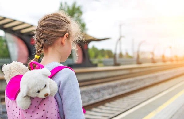 Little girl waiting for train at the railway station.