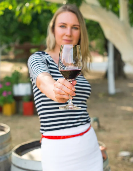 Woman offering glass of red wine at the winery.