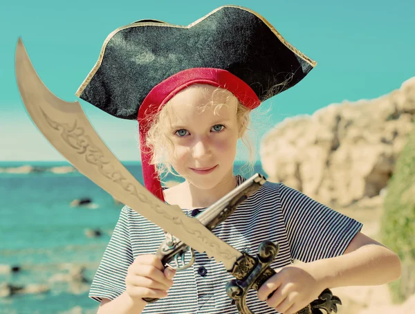 Little girl in pirate costume with sword and old musket gun.